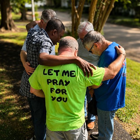 Men praying together on a neighborhood street
